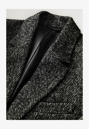 Blazer aus schwarzer und weißer Wolle im Pepita-Muster, mit schmalem Revers und einer einzelnen Tasche, die mit einem glatten schwarzen Futter versehen ist.