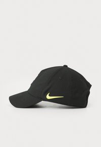 Black cap with a curved visor, featuring a neon yellow Nike logo on the side and embroidered accents. Made of soft fabric.