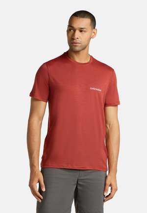 Rød kortærmet t-shirt lavet af blødt stof med rund hals, med et hvidt "icebreaker" logo på venstre bryst.