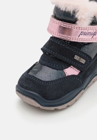Botte de cheville navy et rose avec une douce bordure en fourrure rose, des bandes velcro et un motif texturé sur le dessus. Semelle en caoutchouc avec un léger éclat.