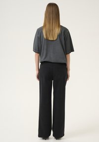 Grå oversize t-shirt med korte ærmer, parret med højtaljede, vidde sorte bukser; enkelt design; ingen synlige mønstre eller hardware.