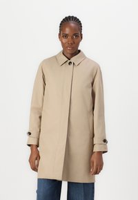 Manteau beige avec un col pointu, des fermetures à bouton et des poches latérales. Fabriqué en tissu lisse avec des manches longues et des boutons aux poignets.