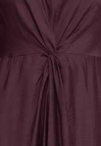 Tissu violet profond avec un nœud central froncé créant de doux plis verticaux et un drapé texturé.