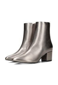 Botines metálicos de color plata con punta afilada y tacón cuadrado, sobre un fondo blanco, que destacan su diseño elegante.