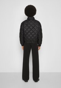 Czarna pikowana kurtka puchowa z stójką, elastycznymi mankietami i pasem, charakteryzująca się błyszczącym wykończeniem i detalami w diamentowy wzór.