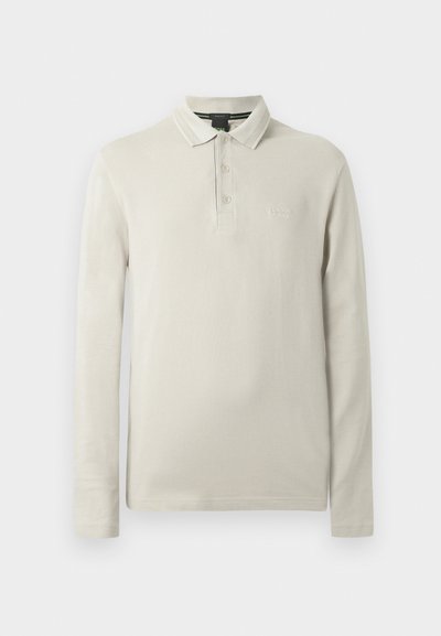 Polo à manches longues de couleur beige clair, confectionné dans un tissu doux. Comprend un col, une patte de boutonnage à trois boutons et une broderie discrète du logo sur la poitrine.