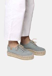 Espadrillas in tela azzurra chiara con suola in juta intrecciata, punta rotonda e lacci beige. Presentano un design cucito e un piccolo dettaglio del logo.