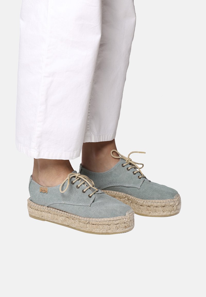 Espadrillas in tela azzurra chiara con suola in juta intrecciata, punta rotonda e lacci beige. Presentano un design cucito e un piccolo dettaglio del logo.