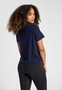 Navyblauw katoenen T-shirt met korte mouwen, ronde hals en een relaxte pasvorm, gecombineerd met een zwarte legging. Glad textuur en een eenvoudig ontwerp.
