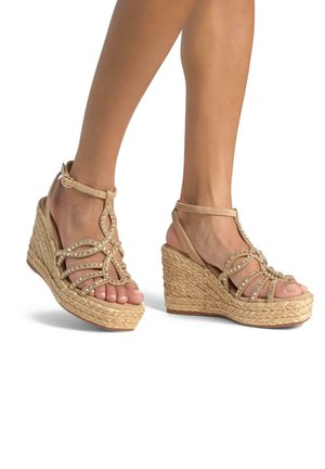 Sandali con zeppa beige con suole in juta intrecciata, adornati con strass e cinturini decorativi. Design aperto che mette in mostra le unghie dei piedi.
