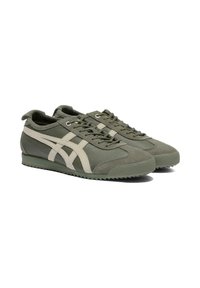 Olive green sneakers with a textured finish, featuring cream accents and lace closure. The sole is textured with a shallow tread pattern.