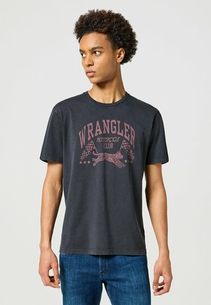 Schwarzes Baumwoll-T-Shirt mit einem verblassten roten Grafikdesign, das den Text "WRANGLER MOTORCYCLE CLUB", einen Tiger und Schachbrettflaggen zeigt. Kurzärmelig.