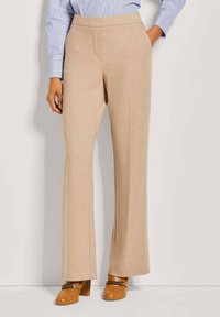 Beige weite Beine Hosen aus weichem Stoff, mit glatter Textur, elastischem Bund und Seitentaschen, kombiniert mit braunen Blockabsatzschuhen.