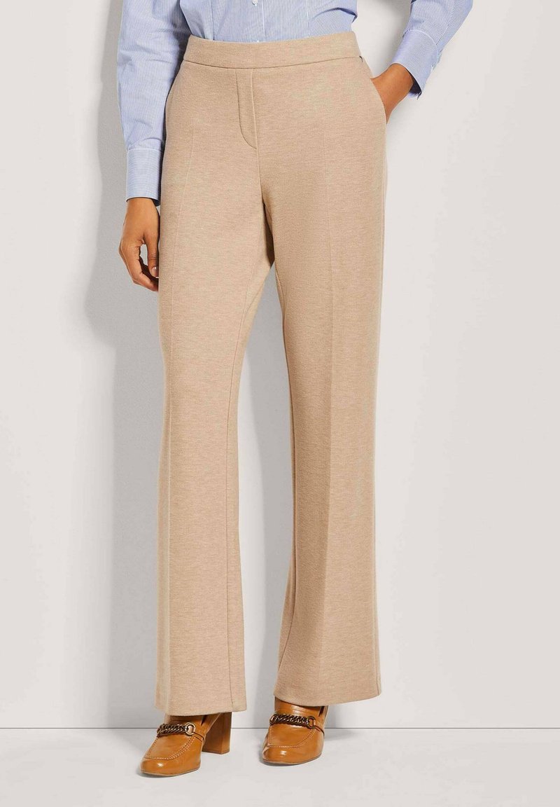 Beige weite Beine Hosen aus weichem Stoff, mit glatter Textur, elastischem Bund und Seitentaschen, kombiniert mit braunen Blockabsatzschuhen.