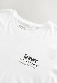 Bela bomba T-shirt iz bombaža z okroglim izrezom. Na sprednji strani je črn natisnjen logotip "BWT ALPINE FORMULA ONE™ TEAM". Mehka tekstura, standardna prileganje.