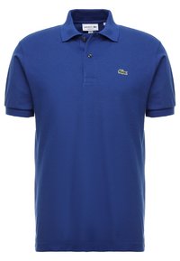 Polo en coton bleu avec un col classique, une patte de boutonnage à trois boutons et un petit logo de crocodile vert sur la poitrine gauche.
