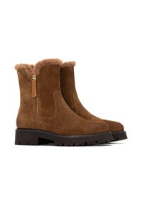 Botas de tobillo de ante marrón con forro de piel sintética, cremallera lateral y suela de goma texturizada. Presentan una puntera redondeada y acentos suaves.