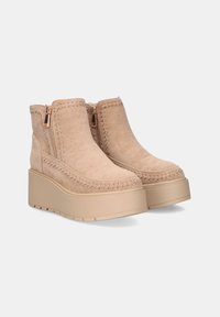 Botas de tobillo de ante beige con suela de plataforma, costuras decorativas y cremalleras laterales para un fácil acceso. Textura suave, diseño casual.