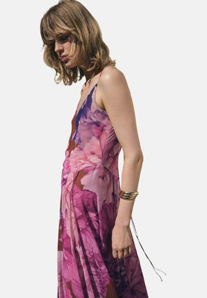 Floral maxi dress with a deep neckline, featuring a pink and purple print. Made of lightweight fabric, it has a flowing silhouette and spaghetti straps.