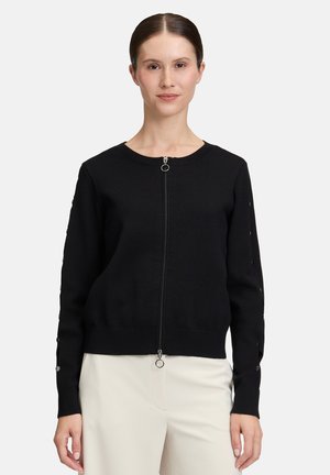 Cardigan nera con zip realizzata in morbido tessuto a maglia. Presenta polsini e orlo a costine, con dettagli decorativi a bottone lungo le maniche.