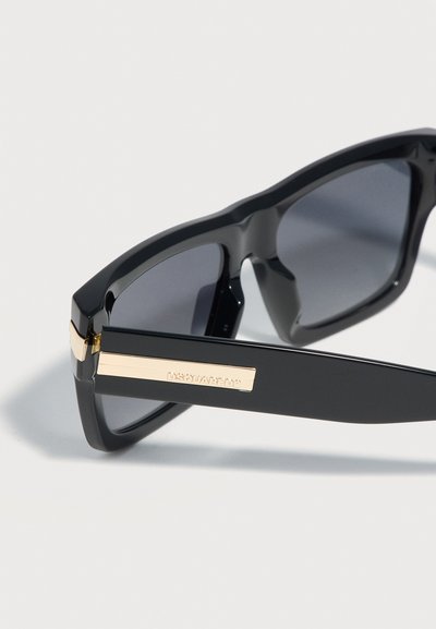 Occhiali da sole rettangolari neri con lenti scure e dettaglio del logo DSQUARED2 dorato sulle stanghette spesse.