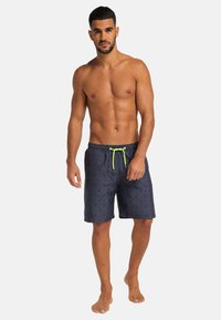 Navy swim shorts with a geometric pattern, elastic waistband, and neon green drawstring. Lightweight fabric, above-the-knee length.