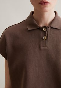 Braun gestreiftes Polohemd mit klassischem Kragen, zwei Knöpfen und kurzen Ärmeln. Der Stoff hat eine strukturierte Oberfläche und eine leicht lockere Passform.