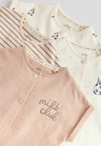 Quatre grenouillères pour bébés en beige et crème, avec le texte « milk club », des imprimés vache et arc-en-ciel, des rayures et des fermetures par boutons-pression.