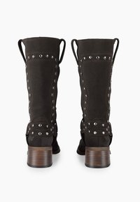 Stivali alti in suede nero con borchie decorative, cinturini in pelle e tacco in legno, caratterizzati da una texture liscia e un design aderente.