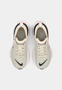 Hellgraue Strick-Sneaker mit einer cremefarbenen Zunge und Akzenten, schwarzem Nike-Swoosh und einer zarten rosa Sohle. Verfügt über Schnürsenkel und eine gepolsterte Innensohle.