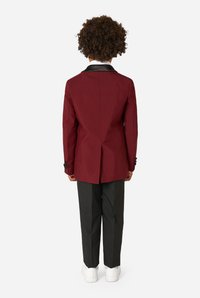 Maroon blazer with black collar, single vent at the back, paired with black trousers and white sneakers. Focus on tailored design.