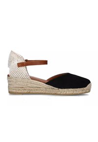 Espadrilla nera in suede con retro intrecciato bianco, cinturino alla caviglia marrone e zeppa avvolta in juta. La suola presenta una finitura testurizzata.