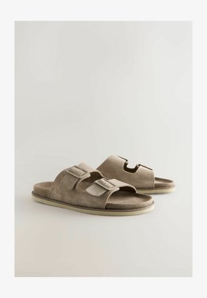 Bézs színű, műbőr szandál két állítható csattal, nyitott orral és texturált talppal, varrott szegéllyel és kivágott részlettel.