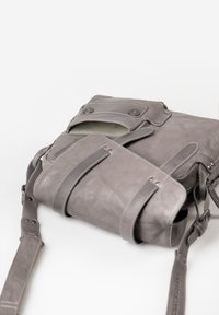 Borsa a tracolla in pelle grigia con chiusura a patta, dotata di dettagli con bottoni, una tracolla regolabile e una superficie testurizzata.