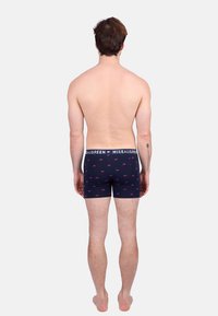 Shorts en boîte pour hommes bleu marine avec des petits motifs d'ours roses, fabriqués en tissu doux, avec une taille élastique blanche portant une marque.