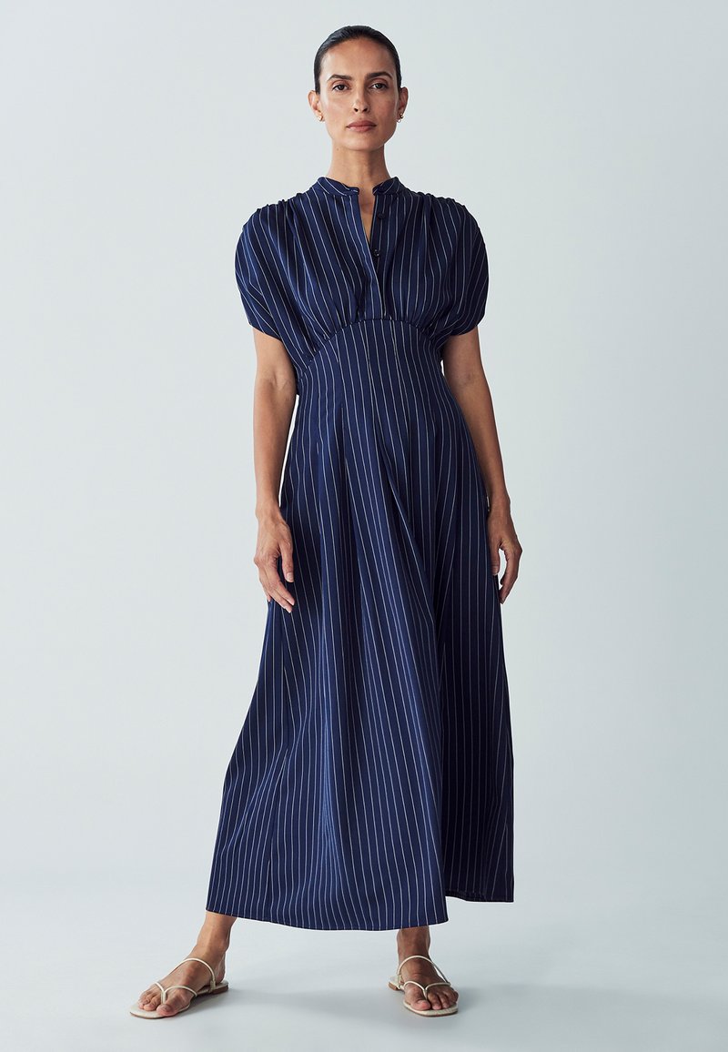 Navy blue, long, striped dress with puffed sleeves, a high neckline, and a cinched waist, made of lightweight fabric.