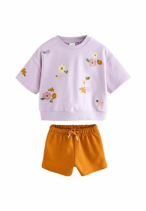 Camisa de algodón lila de manga corta con bordado floral combinada con pantalones cortos de algodón naranjas. La camisa tiene un cuello redondo; los pantalones cortos cuentan con una cinturilla elástica.
