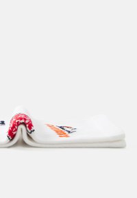 Pair of folded white knit socks with red, blue, and orange playful patterns on a white background.