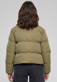Olivengrønn puffjakke med quiltet design, med en kort silhuett, elastiske mansjetter og en jevn, blank tekstur.