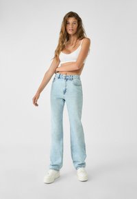 Lyseblå lige ben jeans med høj talje, der har et klassisk fem-lomme design, denim tekstur og slidte detaljer.
