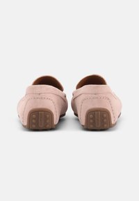 Ζευγάρι μοβ ροζ μοκασίνια οδήγησης από σουέτ με καφέ λάστιχο στη σόλα, φωτογραφημένα από πίσω σε λευκό φόντο.