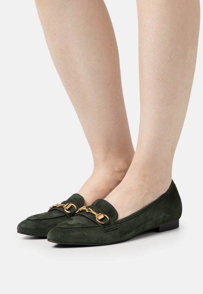 Les mocassins en daim vert présentent des bouts arrondis, une semelle plate, des accents en métal doré et un talon bas. Leur design est élégant avec des coutures minimales.
