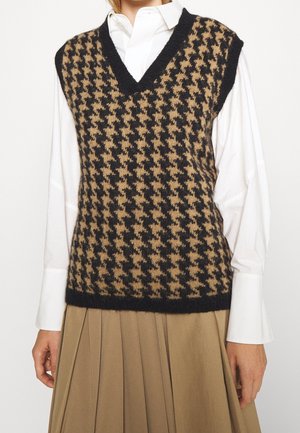 Strickweste mit einem Hahnentritt-Muster in Schwarz und Braun, mit V-Ausschnitt, ärmellosem Design und geripptem Saum. Getragen über einem weißen Hemd.
