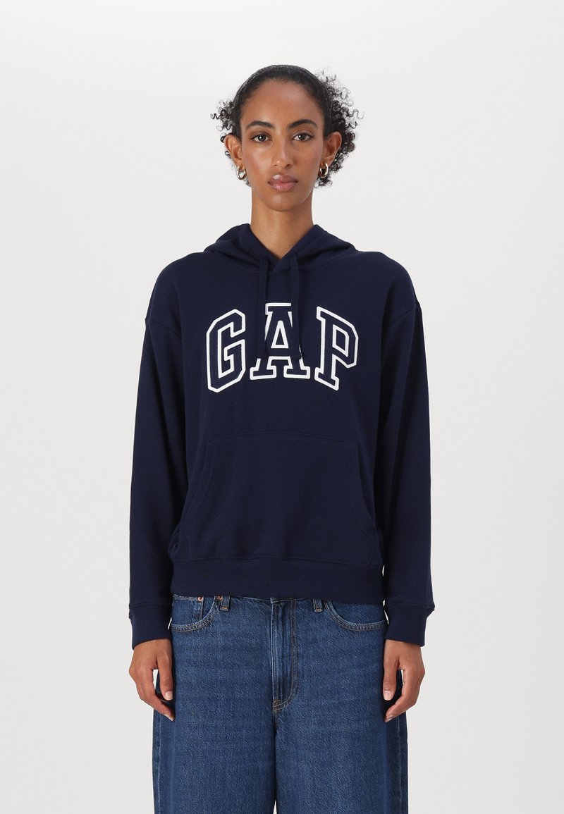 Marinblå hoodie med ordet "GAP" i vit text, med en framficka, dragsko i huvan, samt ribbat nederkant och ärmslut. Avslappnad passform.