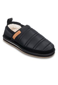 Chaussons noirs à enfiler avec un design matelassé, bordure noire texturée, doublure blanche douce et un accent en cuir marron sur le côté.