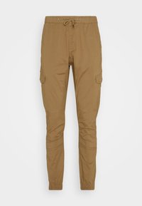 Pantalon cargo slim marron avec poignets élastiques, taille à cordon et poches latérales à rabat, présenté sur un fond uni.