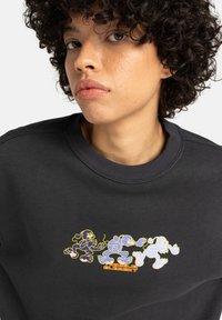Zwarte sweatshirt met kleurrijke cartoonfiguren in blauw en geel op de borst. Lichte textuur met geribbelde kraagdetails.