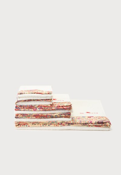 Pile de serviettes blanches pliées avec bordure florale multicolore, disposées de la plus grande à la plus petite sur un fond blanc uni.