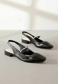 Mustat nahkaiset slingback-kengät, joissa on neliön muotoinen kärki, helmikoristellulla strapilla ja matalalla lohkokannalla. Tasainen pinta, minimalistinen muotoilu.