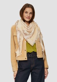 Hellbeige Schal mit floralem Muster, fransenbesetzt, getragen über einem olivgrünen Oberteil und einer hellbraunen Cordjacke, kombiniert mit dunklen Jeans.